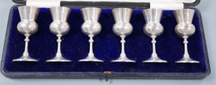 A cased set of six George V silver thistle shaped pedestal tots, E.S. Barnsley & Co, Birmingham,
