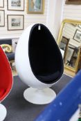 An egg pod chair, in the style of Eero Aarnio, with white plastic shell and rotating base