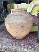 A large Greek style earthenware olive jar on wrought iron stand, height 116cm