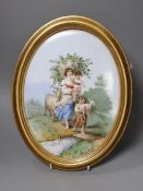 A framed oval porcelain plaque painted with a mother and children and goats