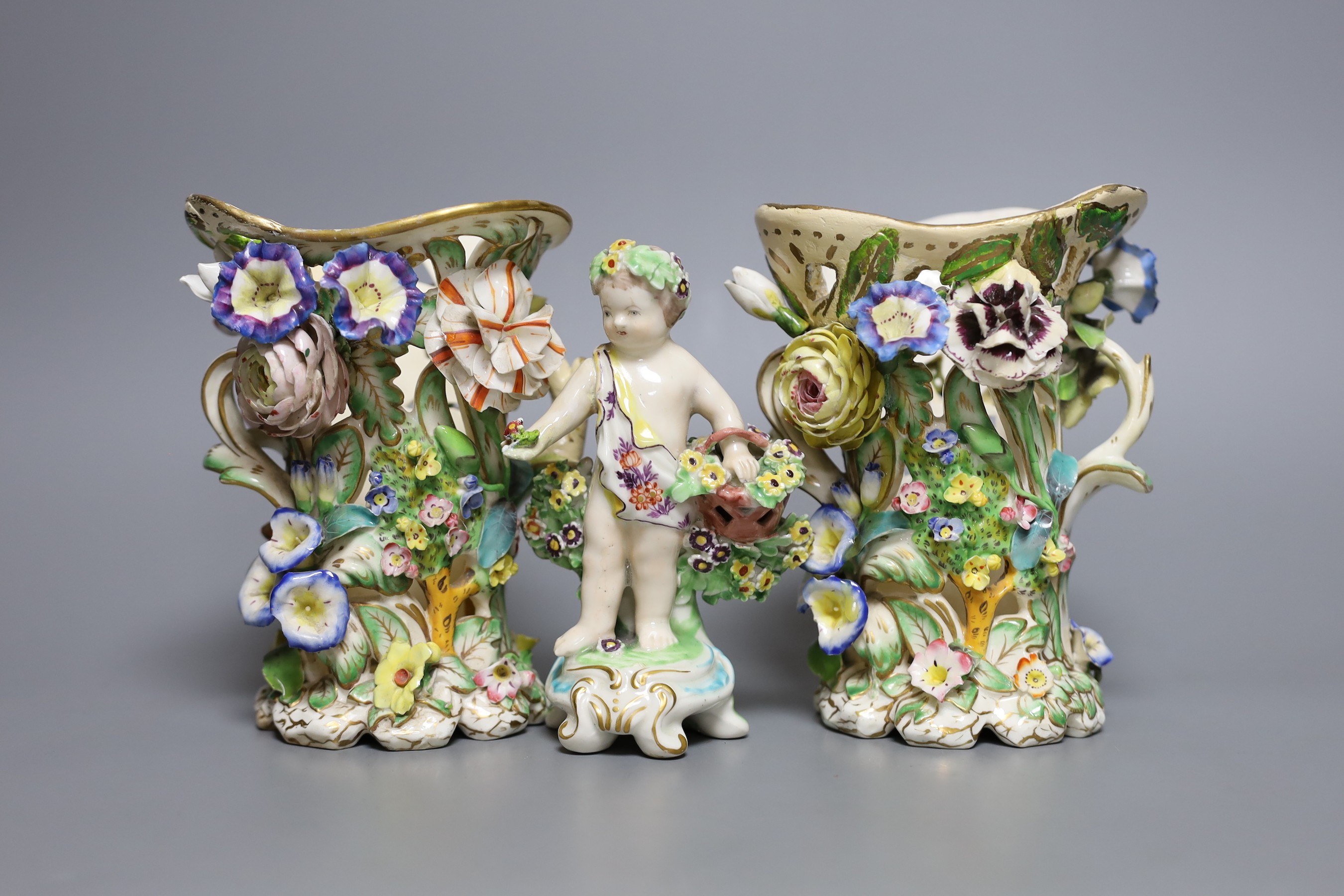 A 19th century Derby figure of a putti with flowers together with two floral encrusted porcelain
