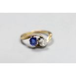 An early 20th century 18ct gold, sapphire and diamond two stone cross-over ring, size L, gross 3.2