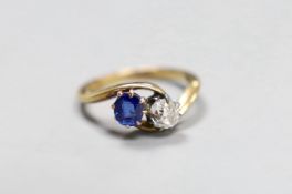 An early 20th century 18ct gold, sapphire and diamond two stone cross-over ring, size L, gross 3.2