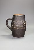A Doulton Lambert black jug, ‘He Who Buys Good Ale Buys Nothing Else’, with silver mount, 19cm tall