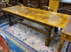 An 18th century style rectangular pale oak refectory dining table with central stretcher and two