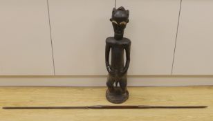 An African Baoule crouched tribal figure, together with a spear, 156cm long