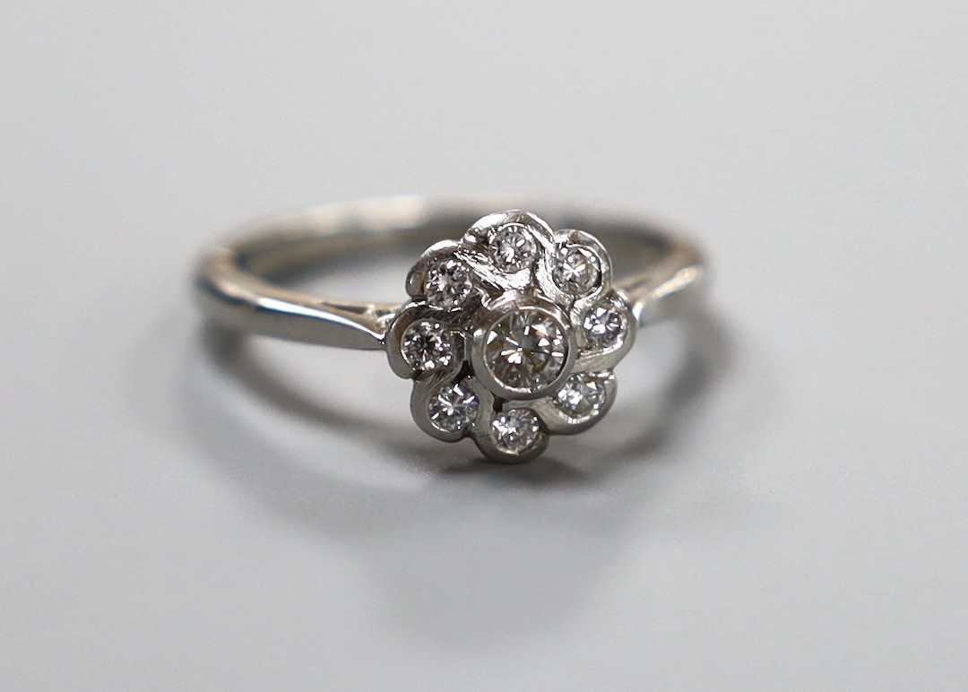 A modern platinum and collet set nine stone diamond flower head cluster ring, size O, gross weight