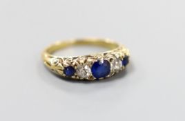 A yellow metal, three stone sapphire and two stone diamond set half hoop ring, with carved