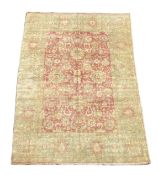 An Indian Agra carpet, with central field of stylised floral motifs on a red ground within a