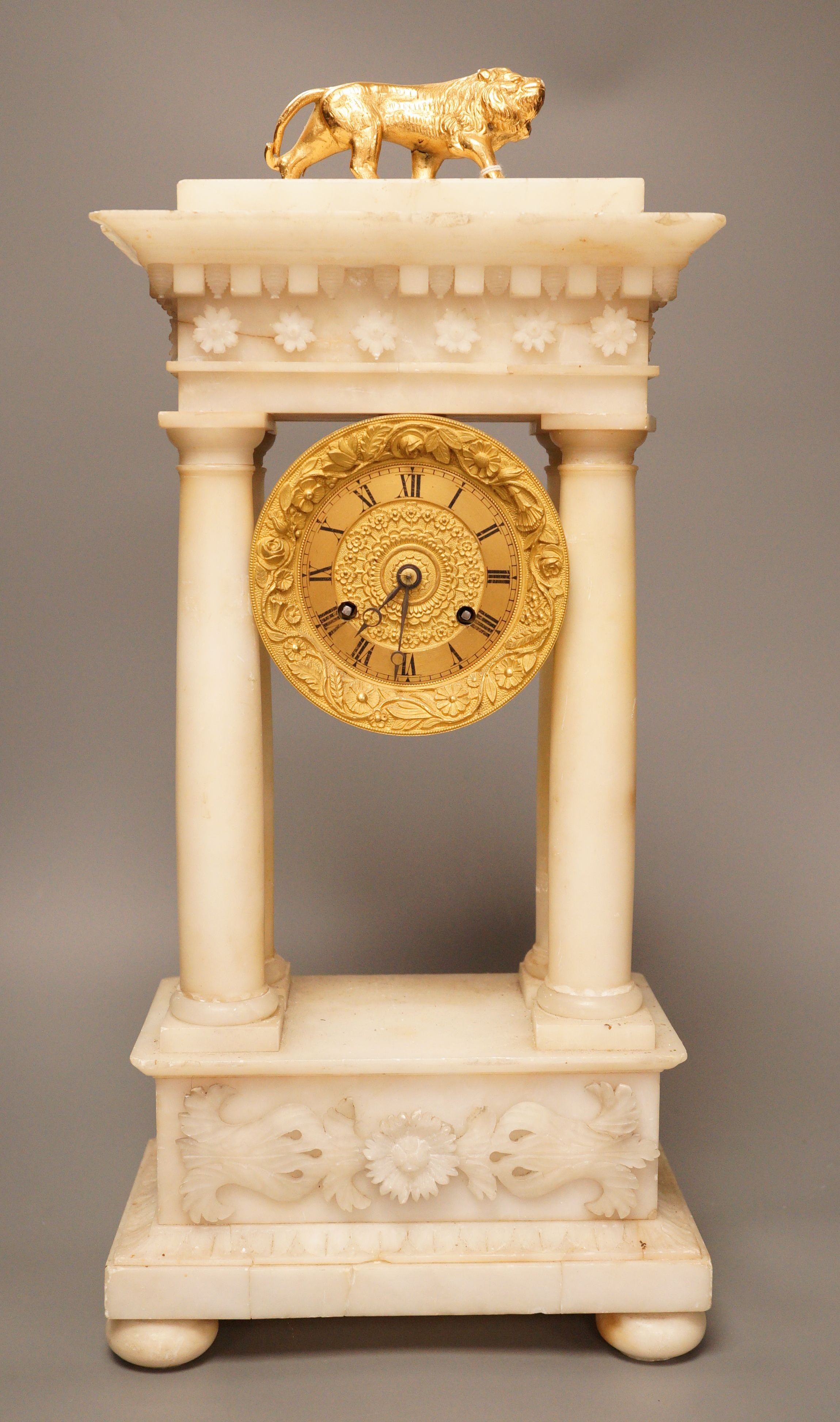 A 19th century alabaster portico clock with a gilt metal prowling lion decoration, 50cm tall