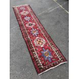 A Caucasian style red ground runner, 264 x 63cm