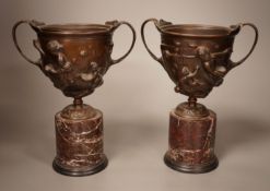 A pair of early 20th century twin handled bronze cups on marble plinth bases, 22cm