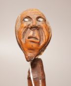 A 19th century continental carved head with glass eyes on associated cane stick. Total length 92cm