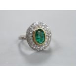 A white metal, emerald and diamond set oval cluster ring, size I/J, gross weight 3.8 grams.