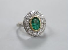 A white metal, emerald and diamond set oval cluster ring, size I/J, gross weight 3.8 grams.