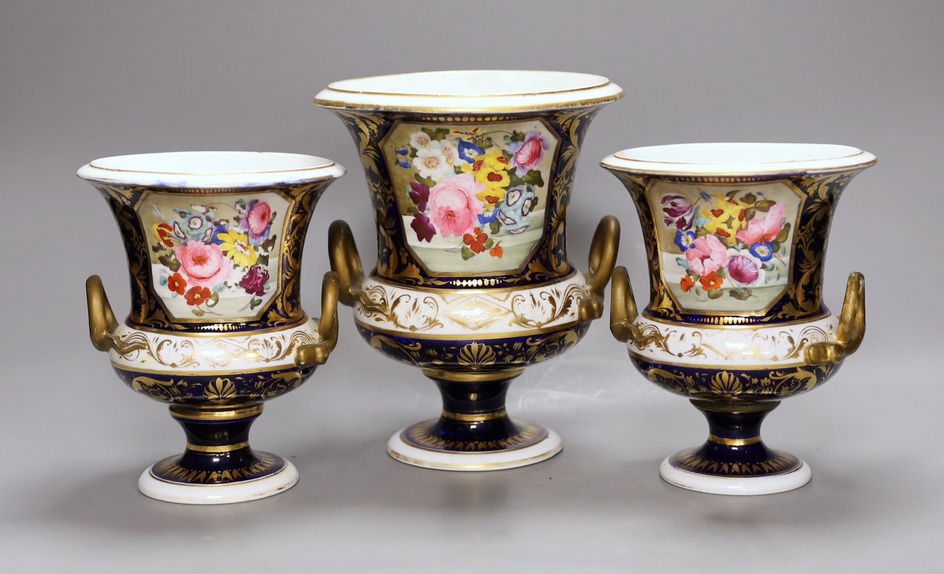 A garniture of three early 19th century floral painted Derby vases, tallest 20cm