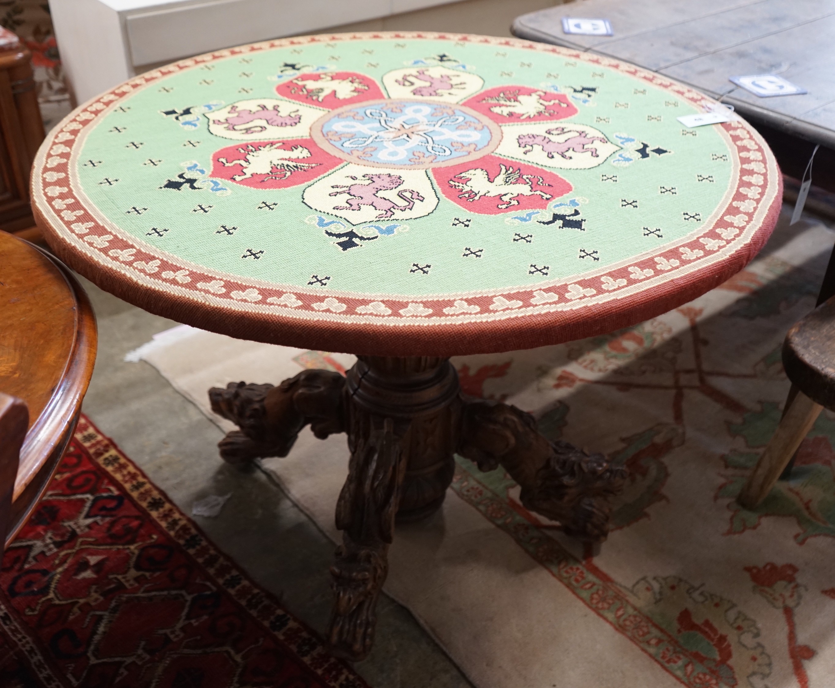 An early 20th century Continental carved oak circular centre table with heraldic tapestry top on