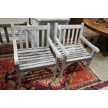 A pair of slatted weathered teak garden elbow chairs, width 60cm, depth 58cm, height 83cm
