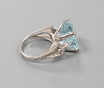 A white metal and single stone square cut aquamarine set dress ring, with diamond set shoulders,