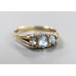 A modern 9ct gold, three stone blue topaz and diamond chip set ring, size W, gross weight 3.8