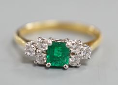 A modern 18ct gold and single stone emerald ring, with six stone diamond set shoulders, size N,