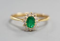 A modern 18ct gold, oval cut emerald and diamond chip set oval cluster ring, size N/O, gross