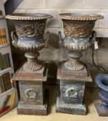 A pair of Victorian style cast iron campana garden urns on square plinths, height 110cm