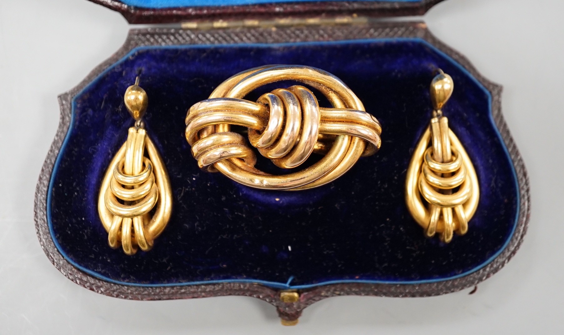 A cased Victorian yellow metal demi parure, comprising a brooch and pair of earrings of entwined