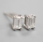 A modern pair of 750 white metal and emerald cut solitaire diamond ear studs, gross weight 1.4