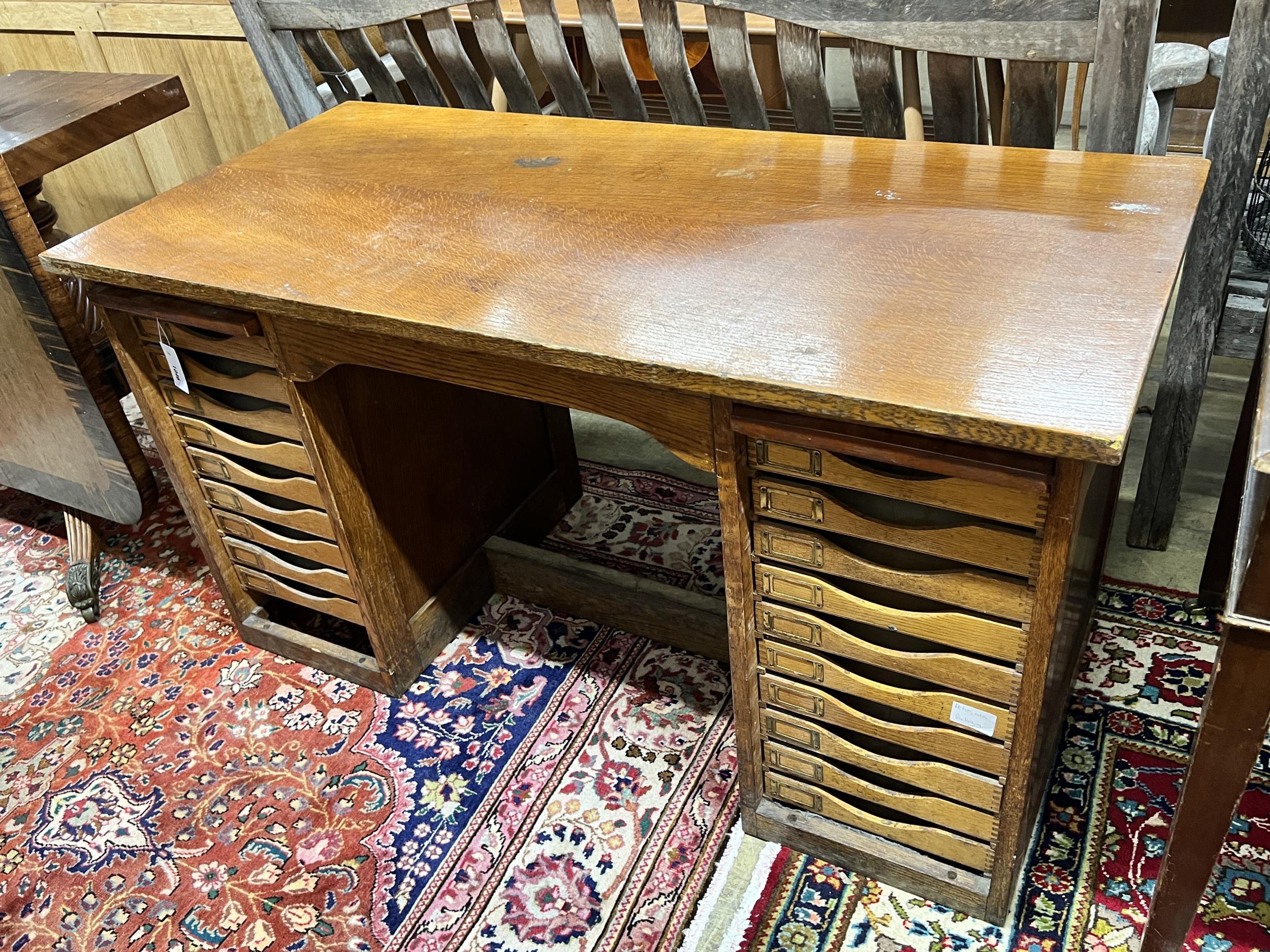 A mid 20th century oak kneehole desk fitted filing drawers, lacking tambour shutters, length