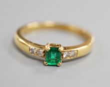 A modern 18ct gold and single stone emerald set ring, with four stone diamond set shoulders, size O,