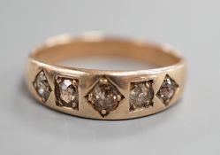 An early 20th century yellow metal and gypsy set graduated five stone diamond half hoop ring, size