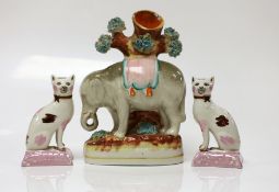 A Staffordshire elephant spill vase and a pair of cats, elephant 17cms high