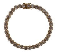 A modern 18k gold and round brilliant cut diamond set line bracelet, set with thirty five stones,