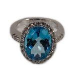 A modern 18k white gold, blue topaz and diamond oval cluster dress ring, with diamond set shoulders,