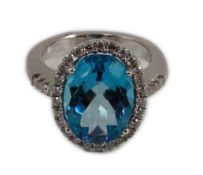 A modern 18k white gold, blue topaz and diamond oval cluster dress ring, with diamond set shoulders,