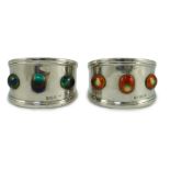 Two similar Edwardian Arts & Crafts silver and enamelled napkin rings, each set with three