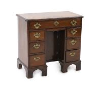 A George III mahogany kneehole desk, fitted six drawers around a central recessed cupboard, on