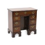 A George III mahogany kneehole desk, fitted six drawers around a central recessed cupboard, on