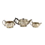 A George IV silver three piece tea set by Benjamin Smith III, of squat melon form, with ornate