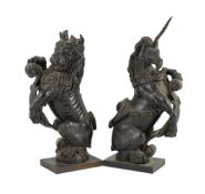 A pair of 18th century carved and ebonised oak heraldic beasts, lion and unicorn, each holding