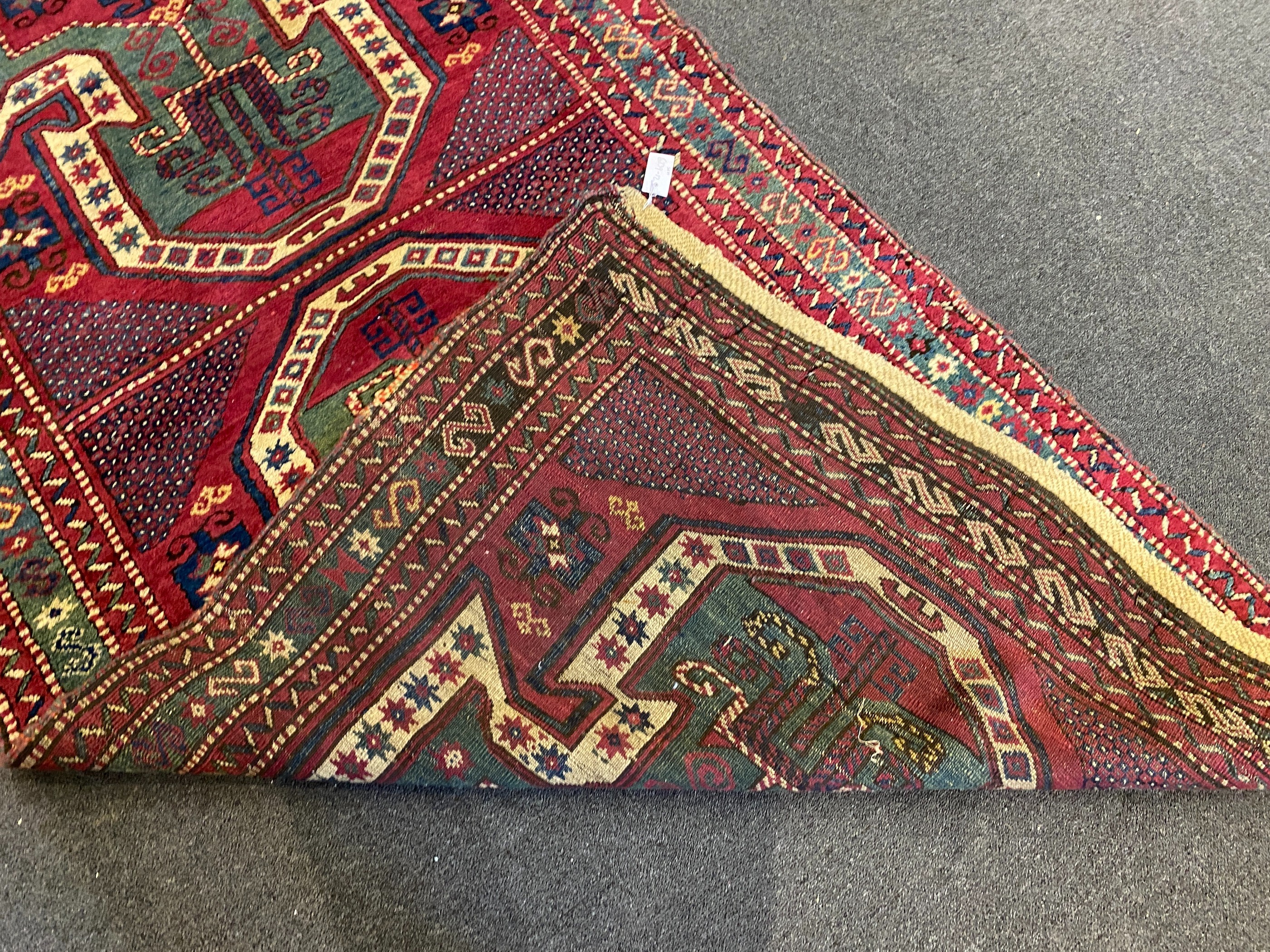 An antique Kazak red ground rug, with double shield motif within a hooked geometric field and triple - Image 5 of 5