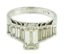 A modern platinum and emerald cut single stone diamond ring, with stepped graduated baguette cut