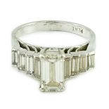 A modern platinum and emerald cut single stone diamond ring, with stepped graduated baguette cut