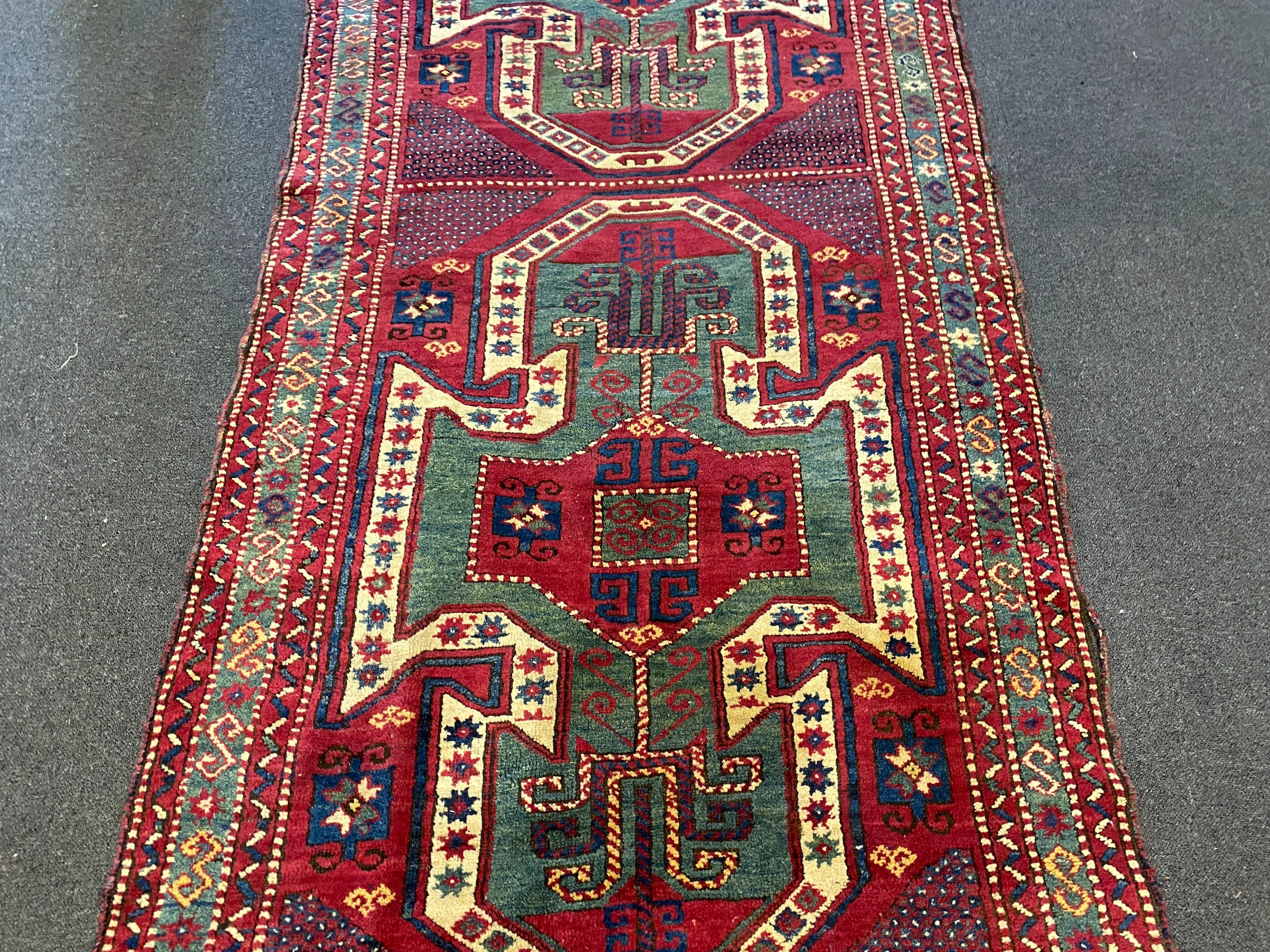 An antique Kazak red ground rug, with double shield motif within a hooked geometric field and triple - Image 3 of 5