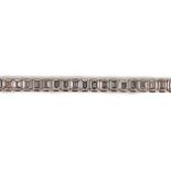 A modern 18ct white gold and emerald cut diamond set line bracelet, the sixty nine stones with a