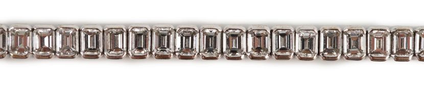 A modern 18ct white gold and emerald cut diamond set line bracelet, the sixty nine stones with a