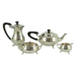 A George V Arts and Crafts three piece planished silver tea set and a similar hot water pot, by
