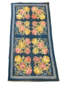 An English needlepoint blue ground carpet, woven with polychrome rose bunches, initialled and