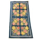 An English needlepoint blue ground carpet, woven with polychrome rose bunches, initialled and